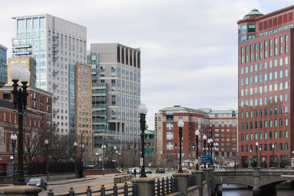 A Providence, Rhode Island skyline featuring multiple lampposts and tall buildings with glass windows and a cloudy sky.