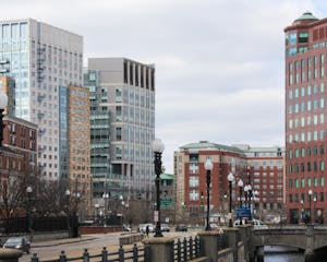 A Providence, Rhode Island skyline featuring multiple lampposts and tall buildings with glass windows and a cloudy sky.