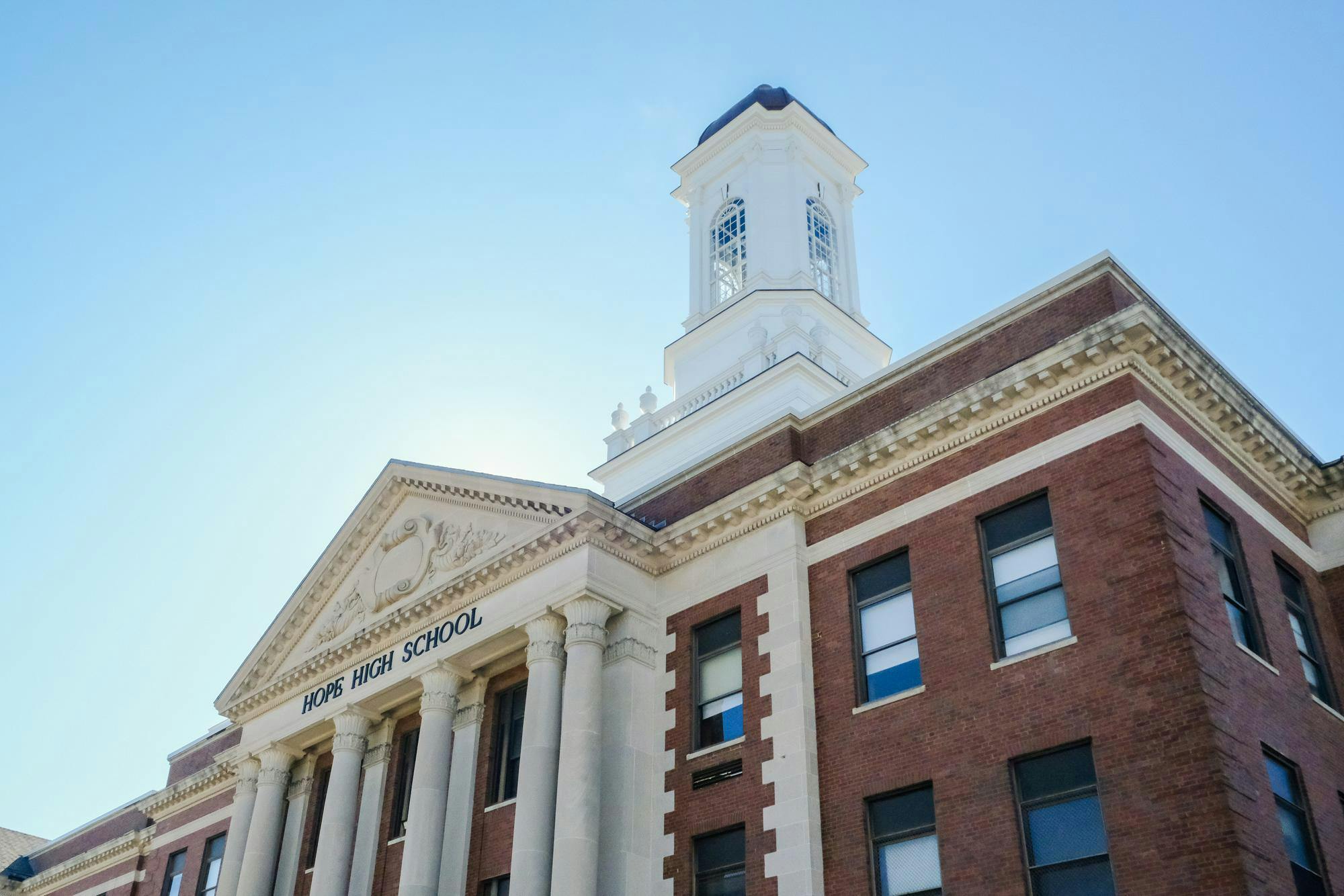 A photo from a low angle of Hope High School -- a brick building with a white bell tower and white details. 