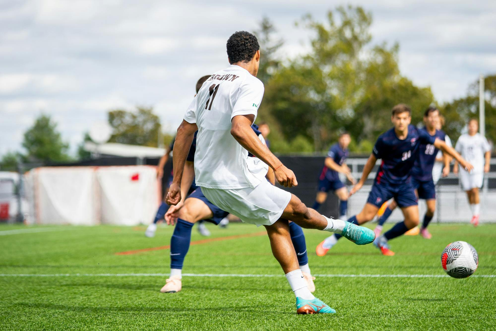 Photo of Jamin Gogo Peters ’26 captured mid-strike, kicking the ball down the left flank around Penn defenders.
