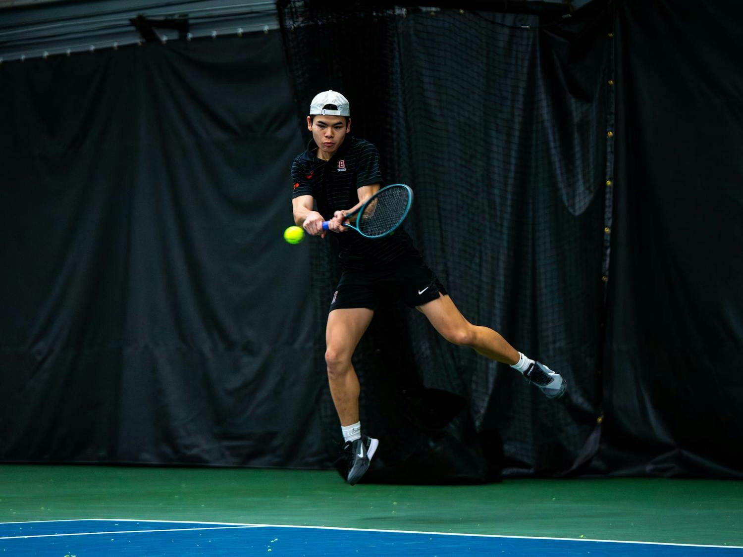 Action shot of a Brown tennis athlete swinging toward the ball.