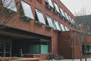 Watson Institute building with multiple bikes in the front and trees on the right. 