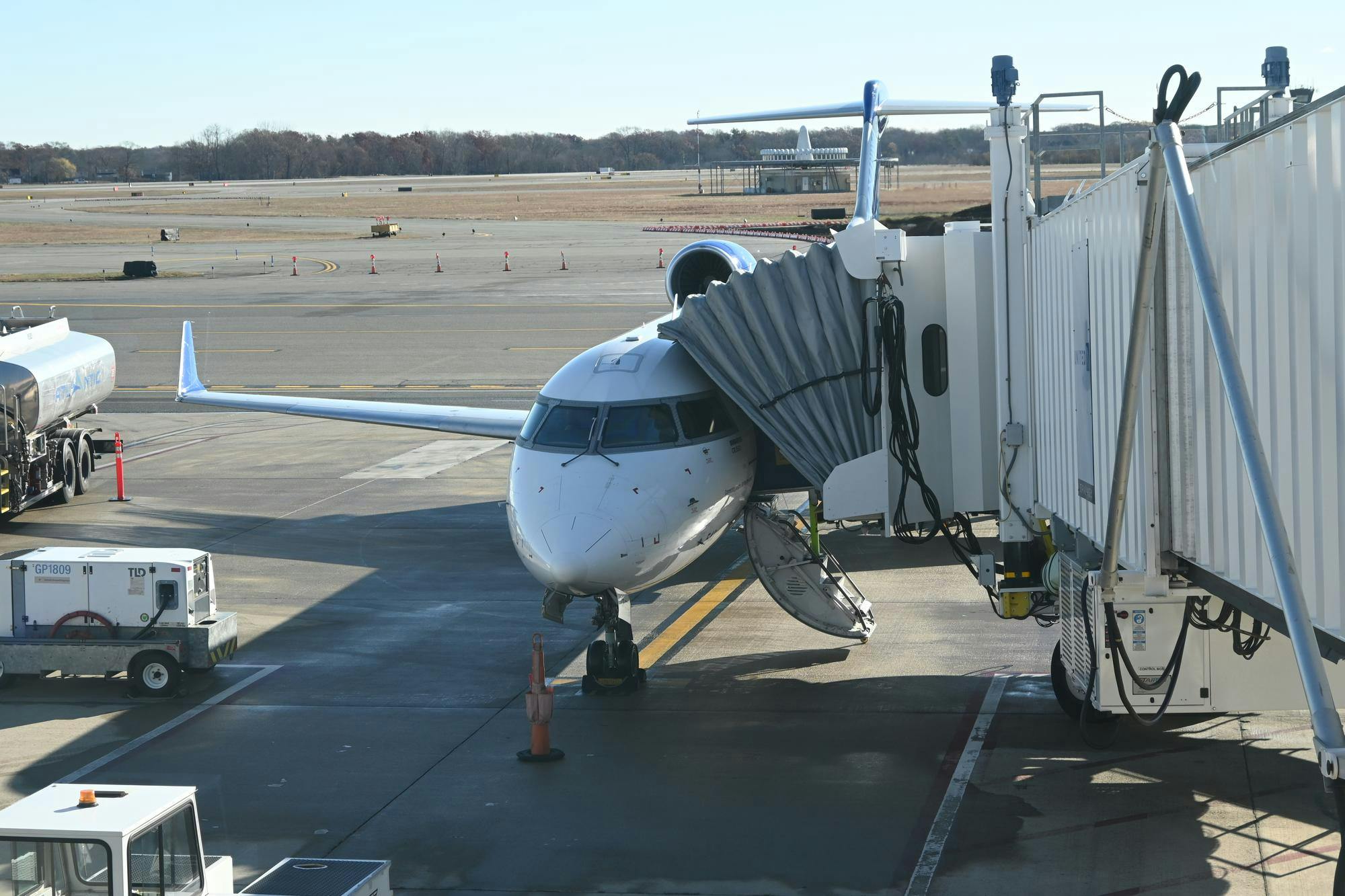 A plane sits on the runway with a walkway attached. 