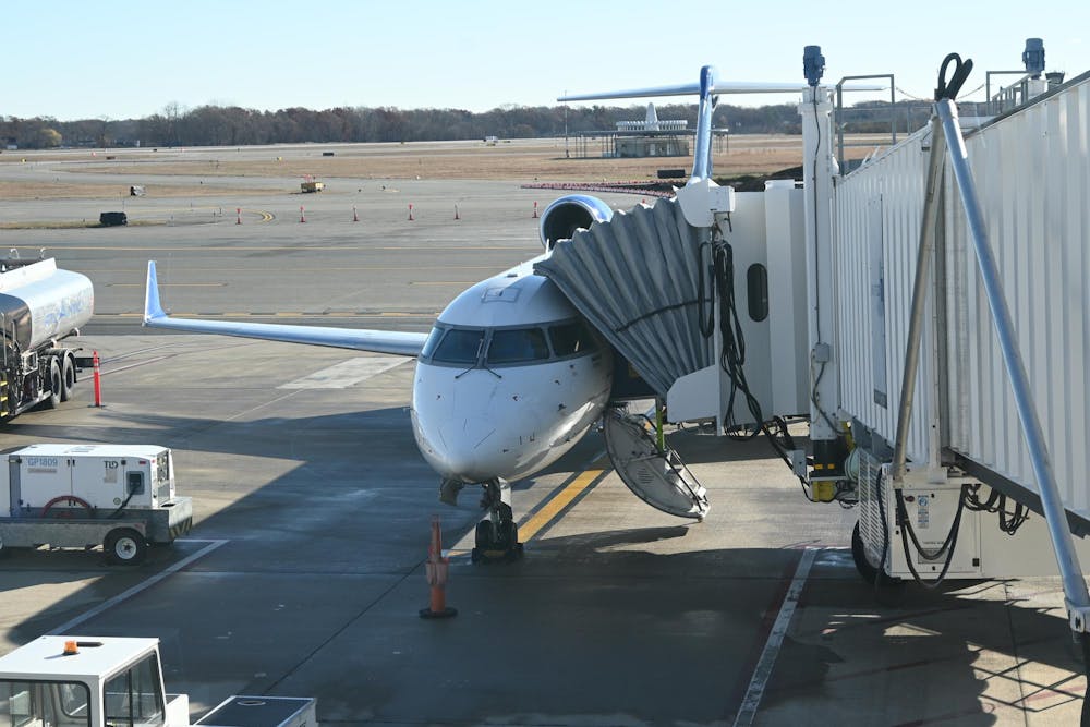 A plane sits on the runway with a walkway attached. 