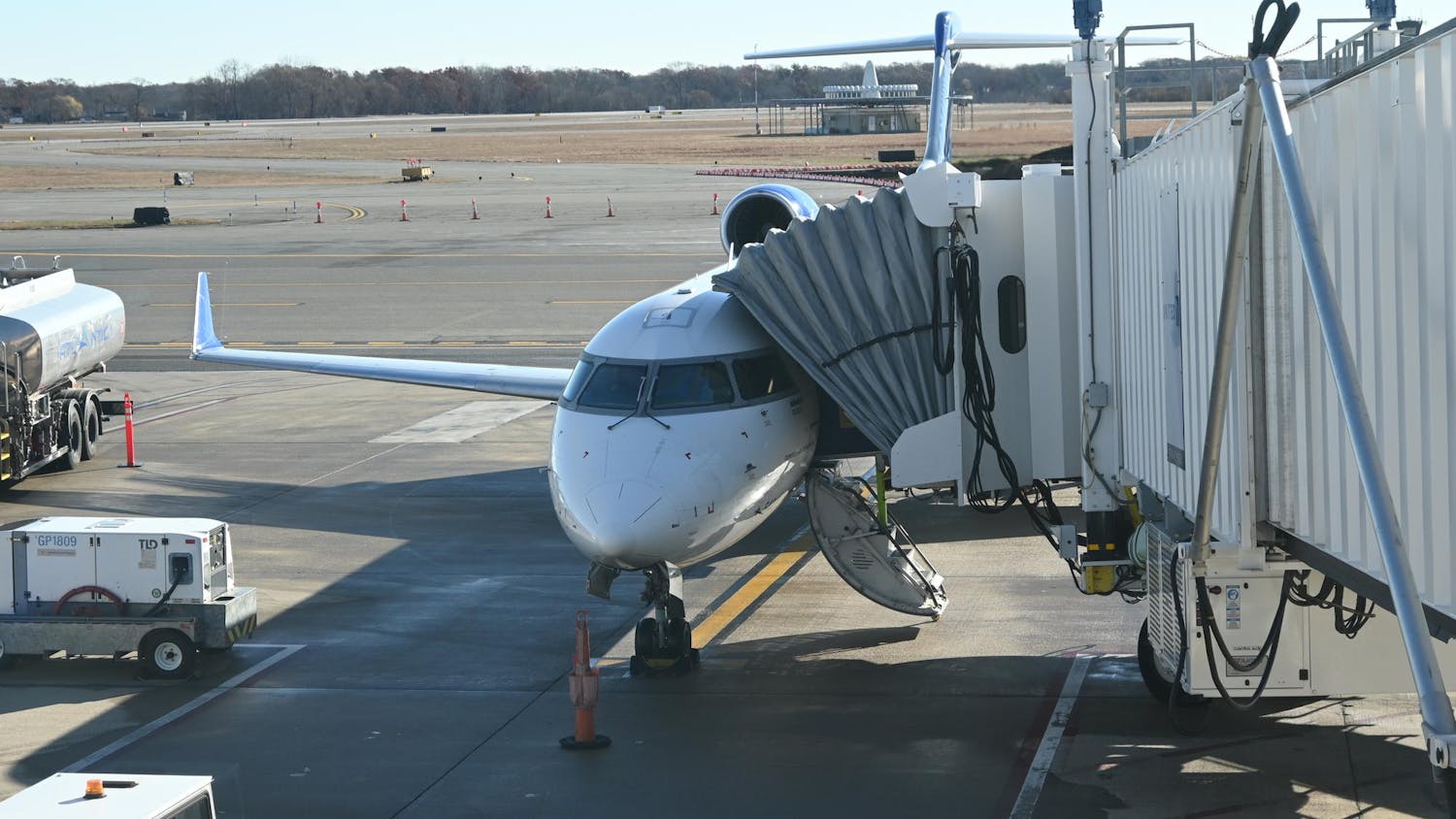 A plane sits on the runway with a walkway attached.