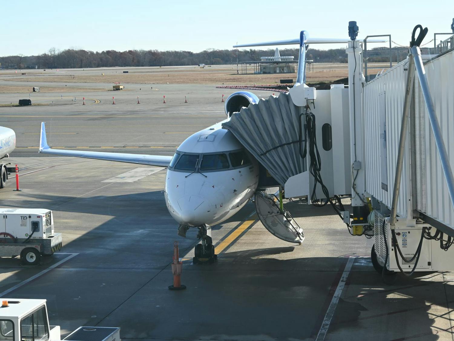 A plane sits on the runway with a walkway attached.