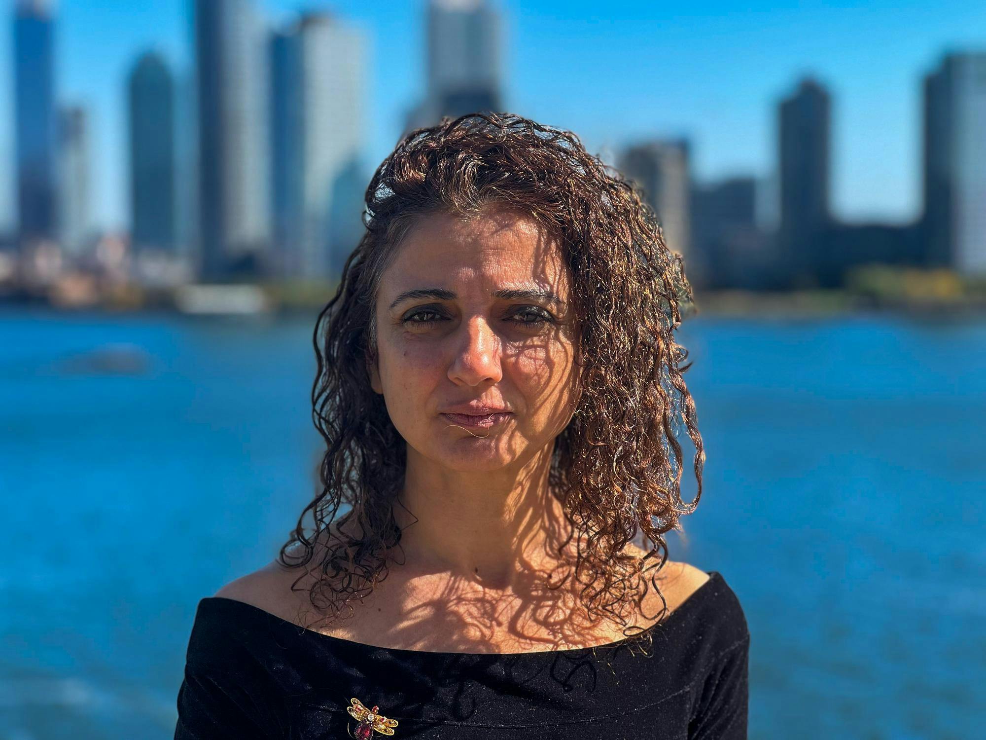 Photo of Palestinian novelist and journalist Ibtisam Azem in front of water.