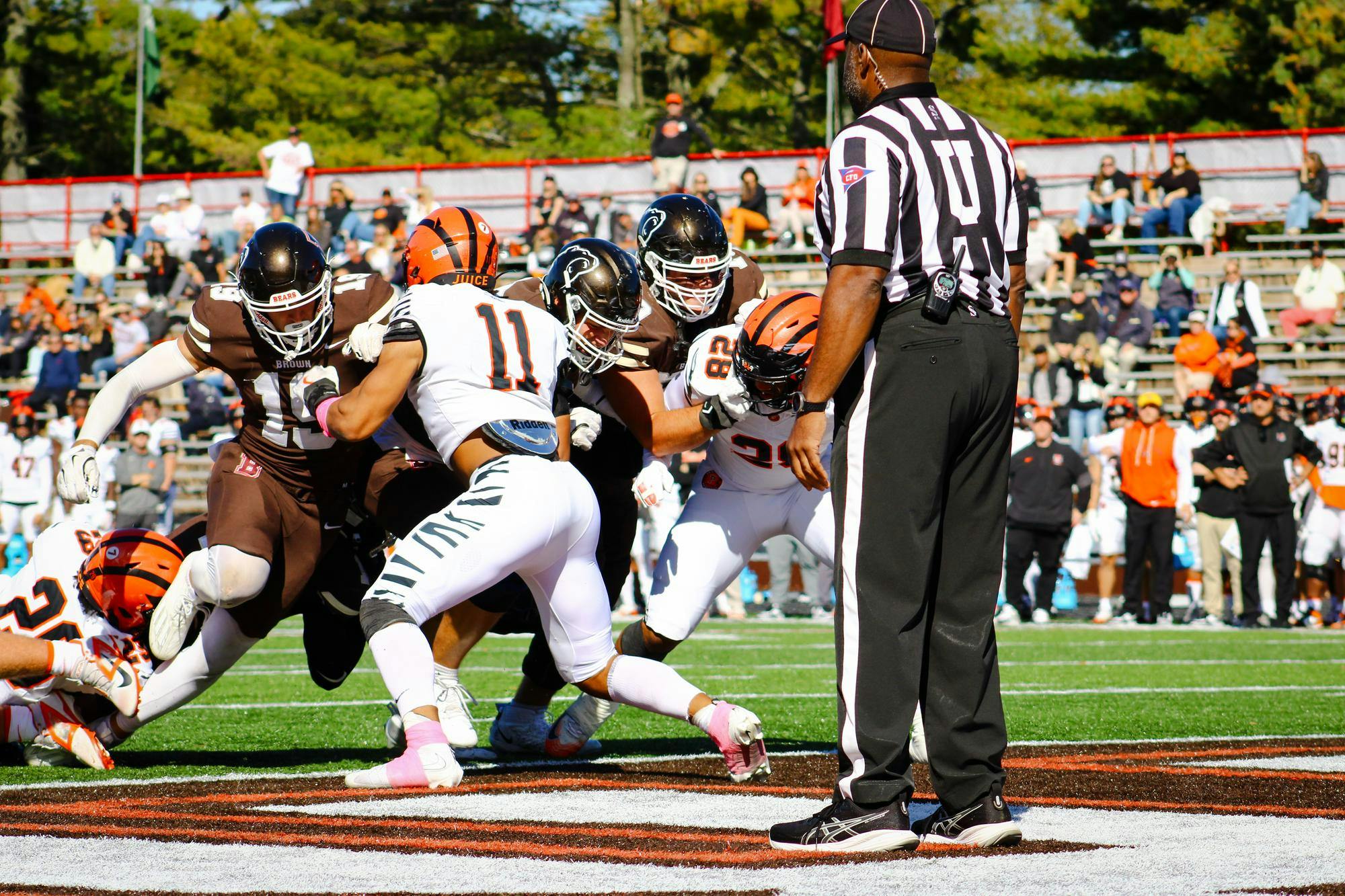 Princeton and Brown football players running into each other, tackling.