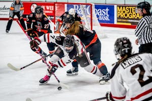 A photo of two hockey players battling for the puck in front of the net.