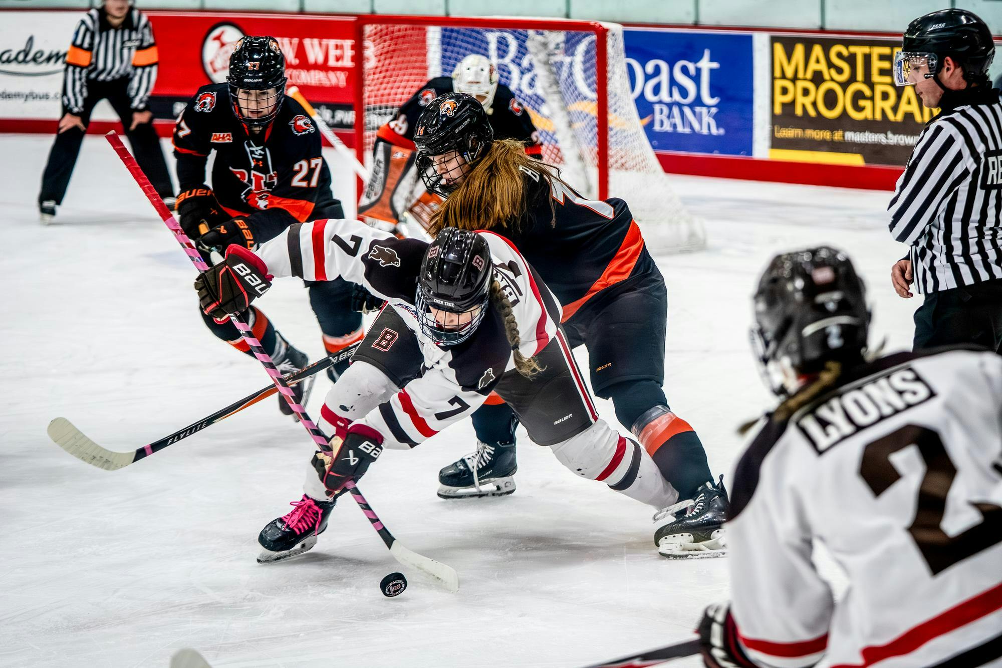 A photo of two hockey players battling for the puck in front of the net.