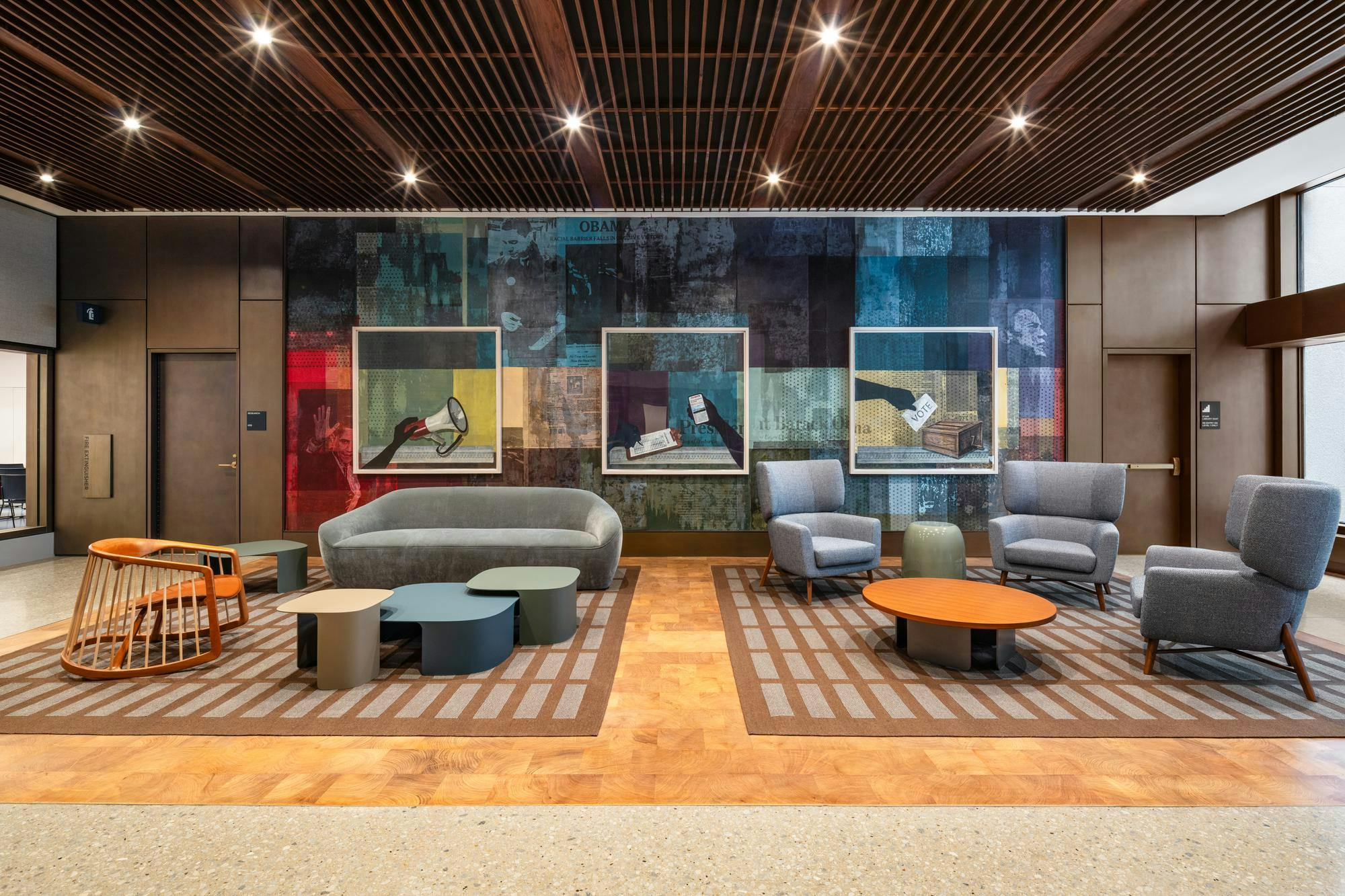 A photo of a room with couches and chairs and collage artwork on the wall. 