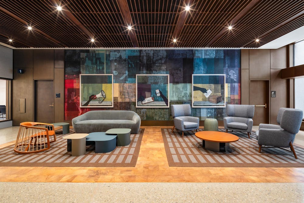 A photo of a room with couches and chairs and collage artwork on the wall. 