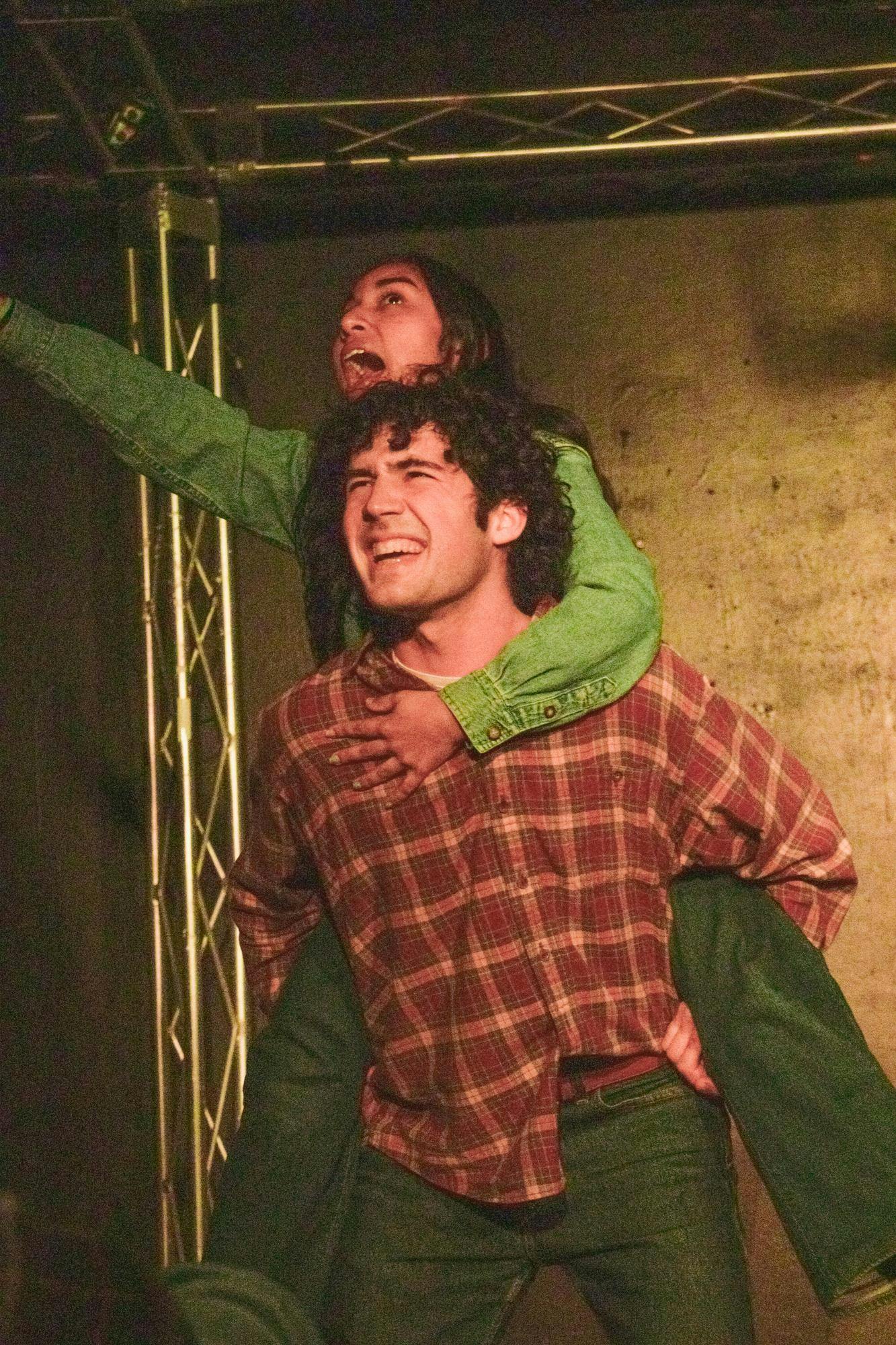 A man holds a woman on his back as she yells.