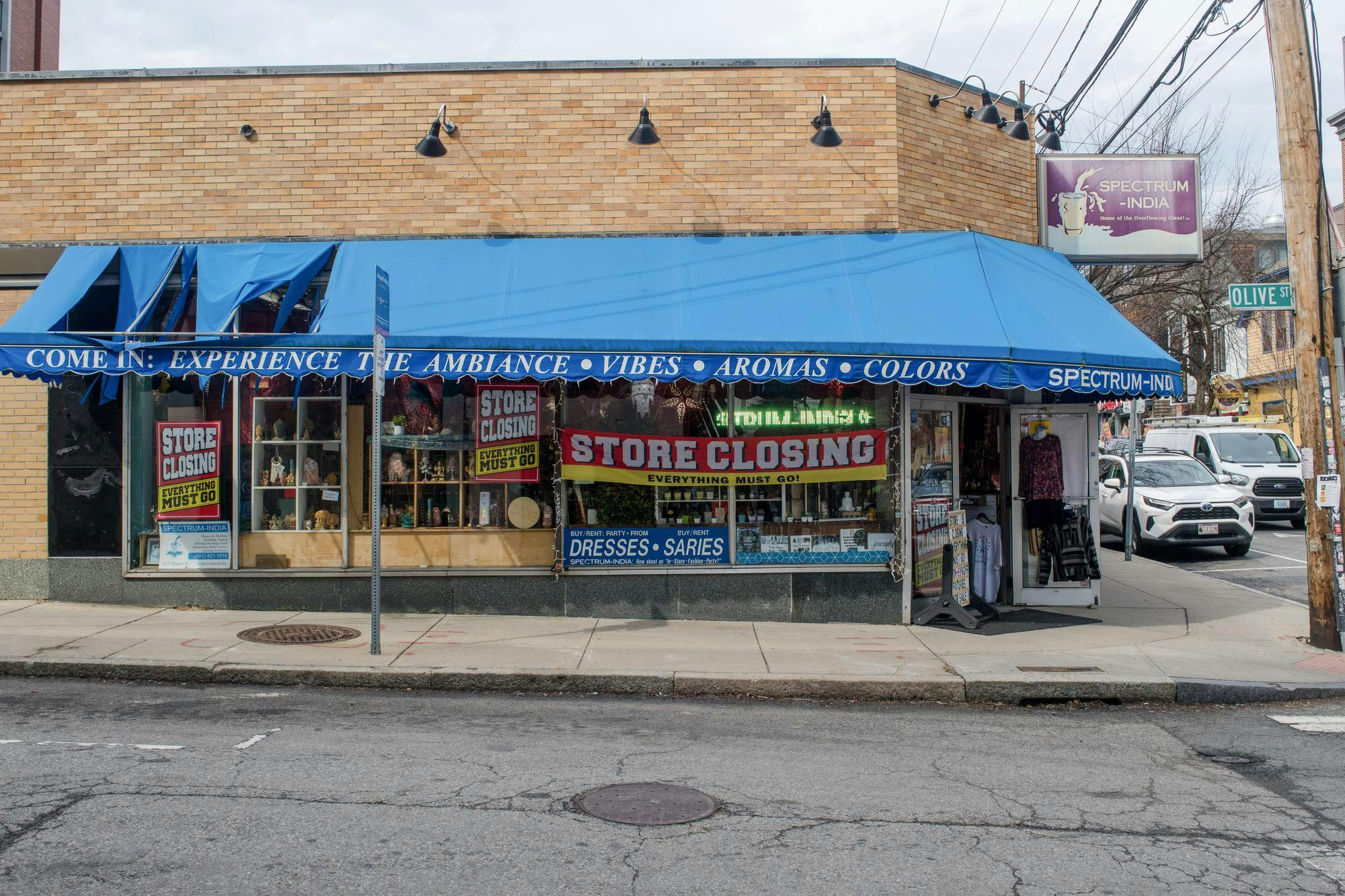 A photo of the exterior of Spectrum India. A building with a blue awning and a sign in the window that reads “STORE CLOSING, EVERYTHING MUST GO.”