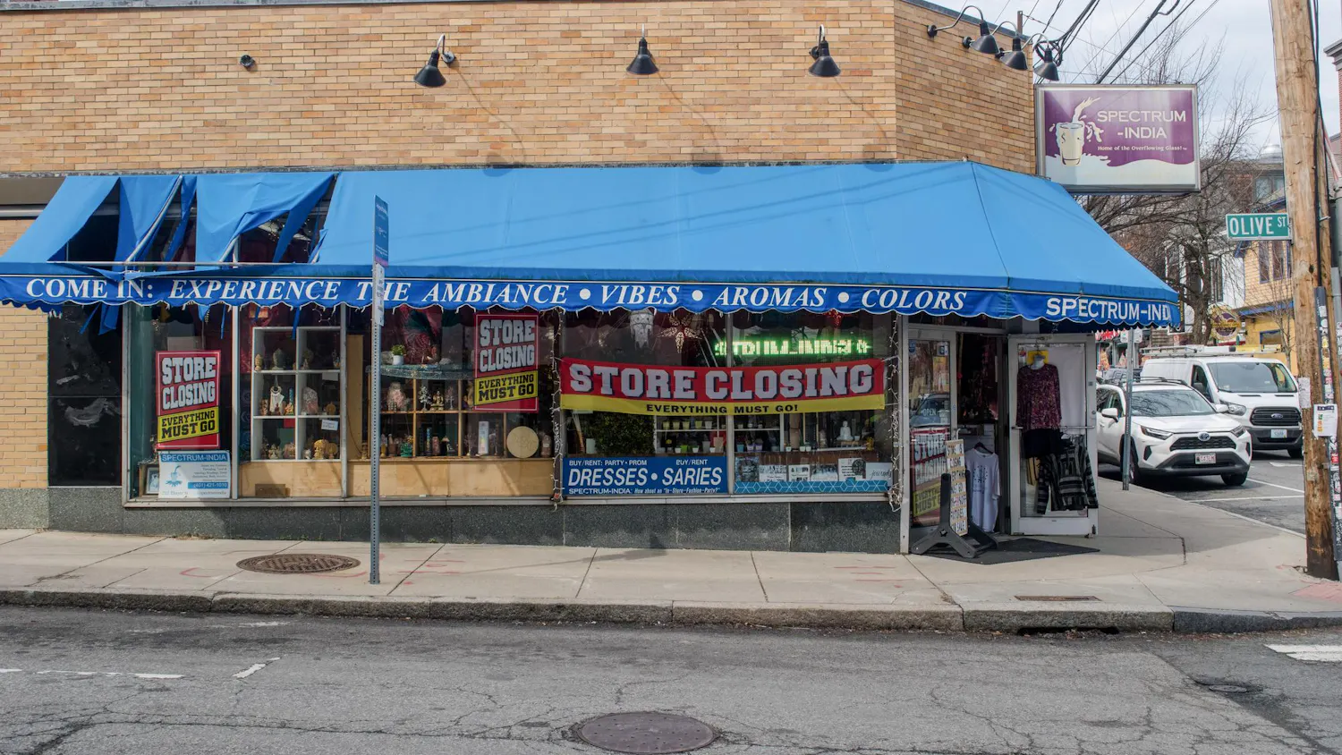 A photo of the exterior of Spectrum India. A building with a blue awning and a sign in the window that reads “STORE CLOSING, EVERYTHING MUST GO.”
