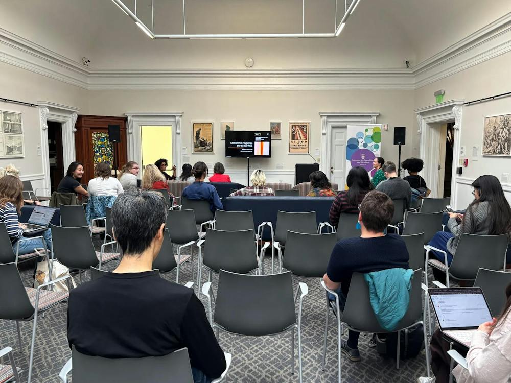 A photo of a room with roughly 20 chairs arranged facing a screen mounted at the front of the room. About half of the chairs are occupied.