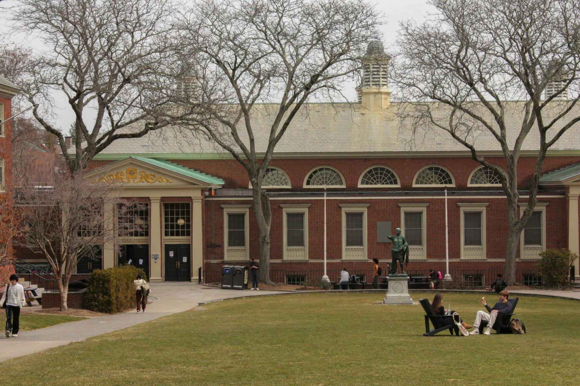 A photo overlooking students mingling in front of the Sharpe Refectory, a dining hall at Brown. 
