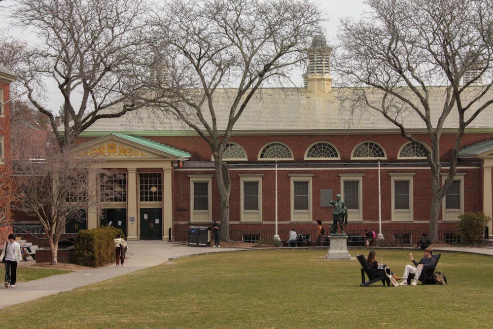 A photo overlooking students mingling in front of the Sharpe Refectory, a dining hall at Brown. 