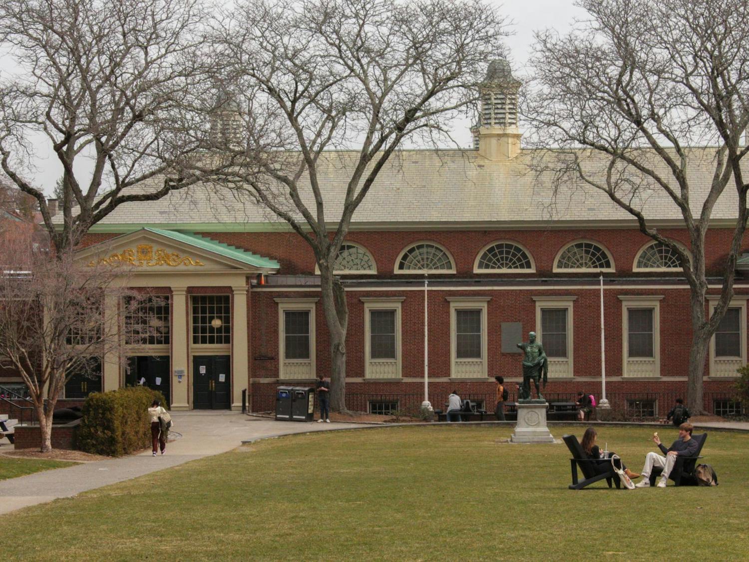 A photo overlooking students mingling in front of the Sharpe Refectory, a dining hall at Brown.