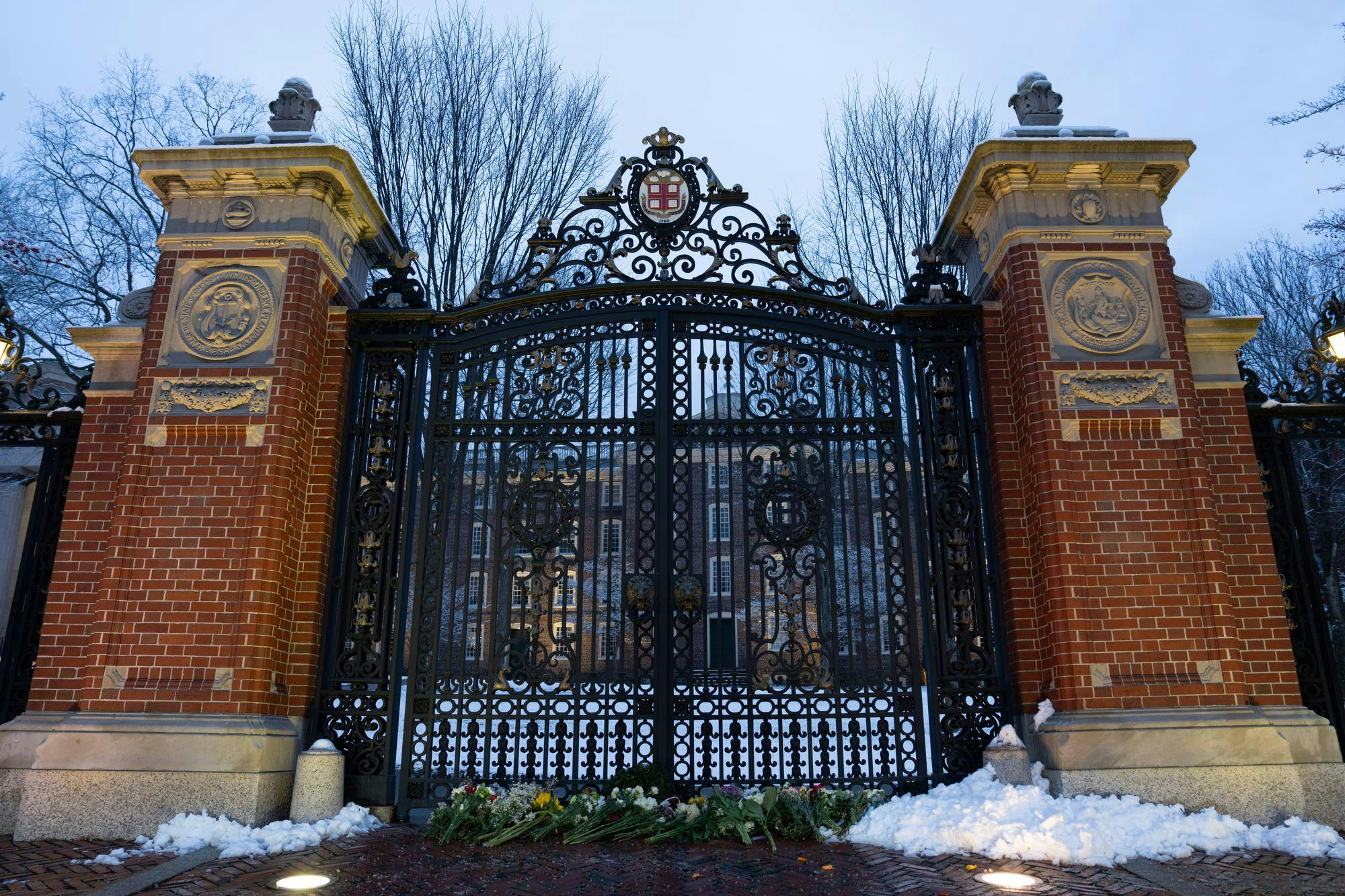 A photo of the Van Wickle Gates with snow and flowers at the bottom of the gates.