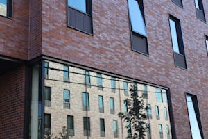 Close image of a Brown University dorm exterior. It is a brick building with another brick building reflected in a large window.
