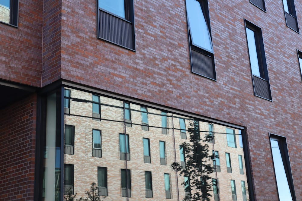 Close image of a Brown University dorm exterior. It is a brick building with another brick building reflected in a large window.