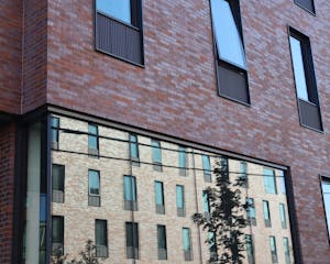 Close image of a Brown University dorm exterior. It is a brick building with another brick building reflected in a large window.