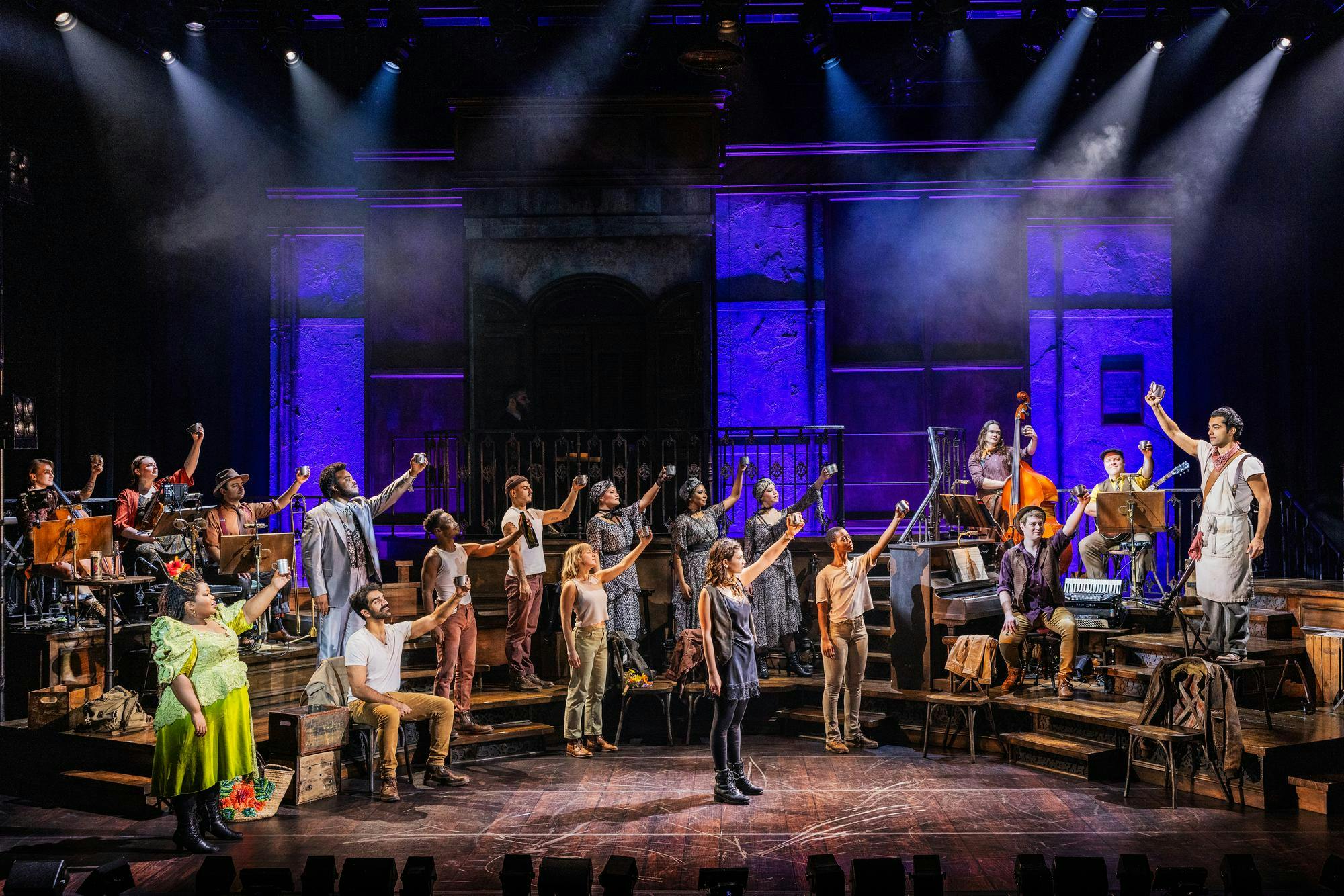 The cast of Hadestown, with drinks in hand, raising their hands high in cheers during Oct. 17’s performance at Walter Kerr Theatre in New York.