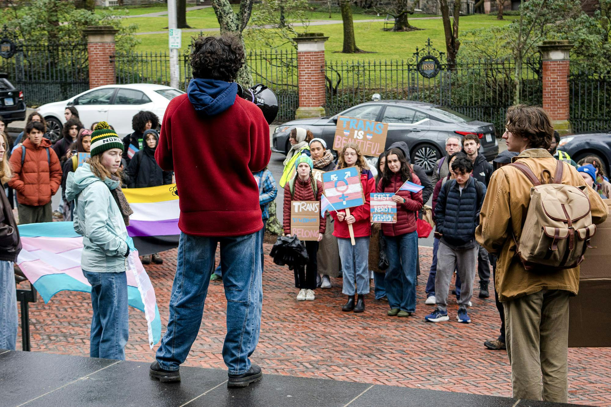 A photo of a trans rights protestor rallying in front of a crowd at the John D. Rockefeller Library.