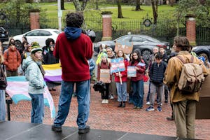 A photo of a trans rights protestor rallying in front of a crowd at the John D. Rockefeller Library.