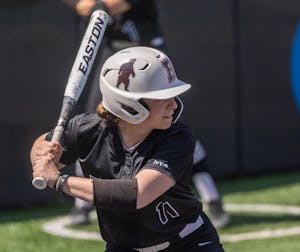 Maggie Foxx ’28 with a softball bat raised behind her head during a game.

