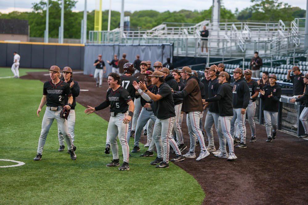 Baseball team emerges from the dugout in celebration, screaming and clapping hands. 
