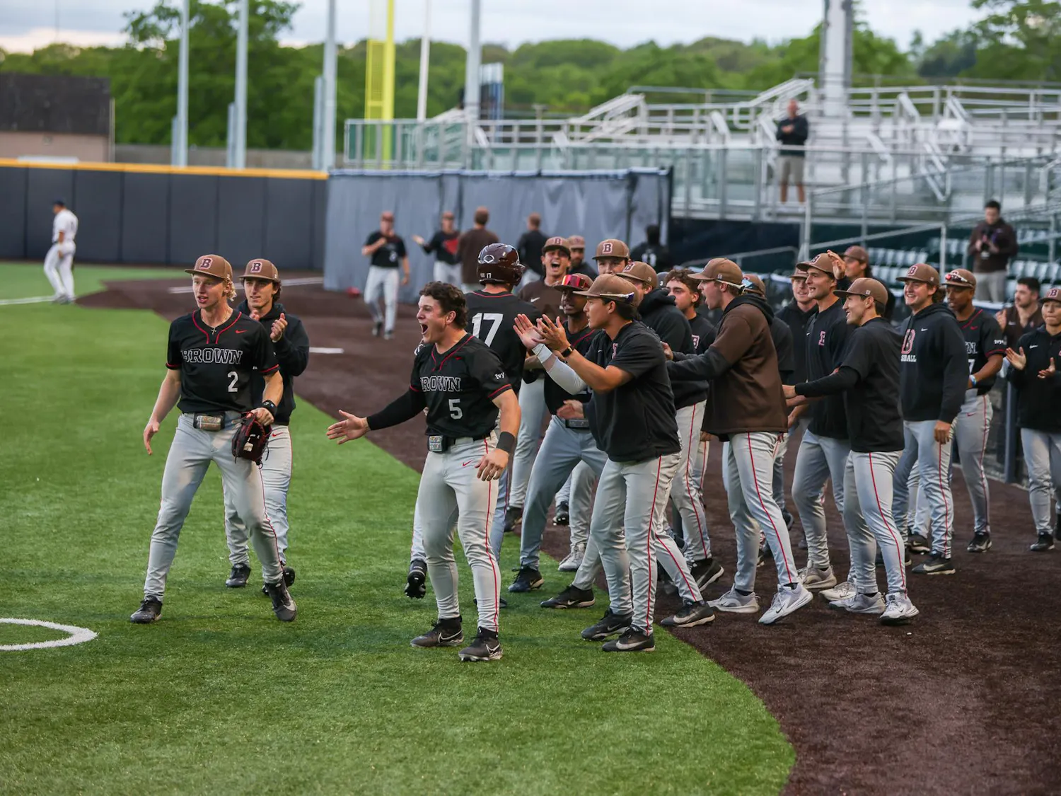 Baseball team emerges from the dugout in celebration, screaming and clapping hands.