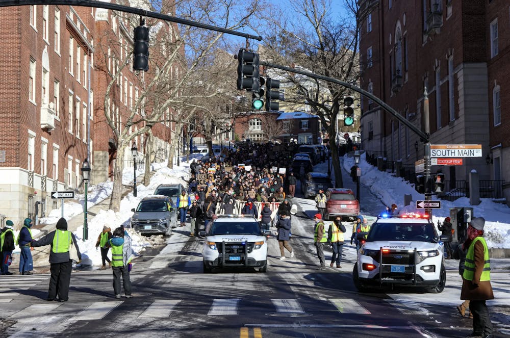 Photo of a group of protestors walk down a hill, following a Providence Police Department vehicle.