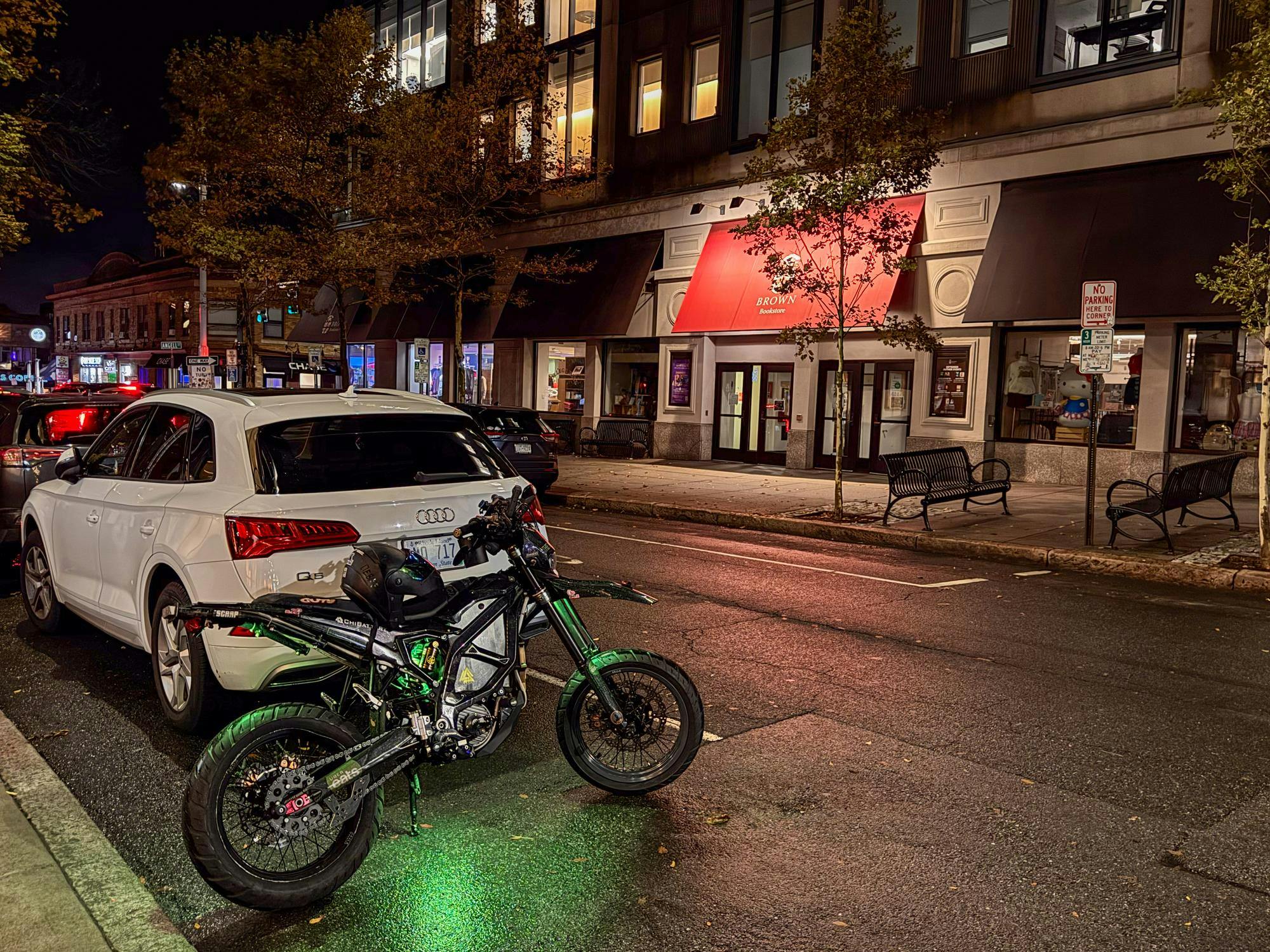 Photo of a motorcycle parked next to a white car on Thayer Street.