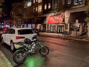 Photo of a motorcycle parked next to a white car on Thayer Street.