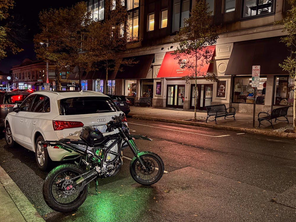 Photo of a motorcycle parked next to a white car on Thayer Street.
