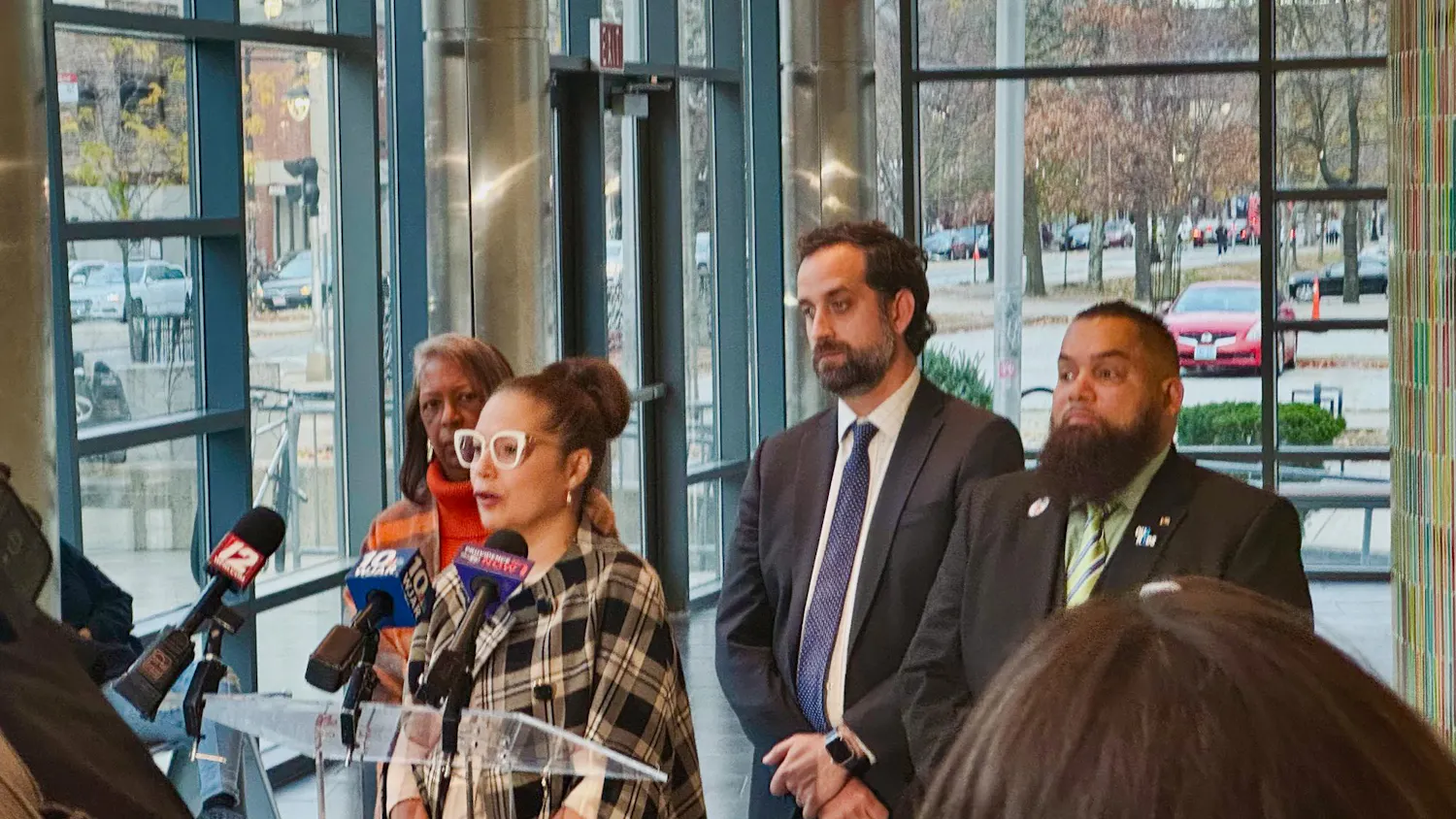 Commissioner of Elementary and Secondary Education Angélica Infante-Green speaks into three microphones for local news stations at a press conference.