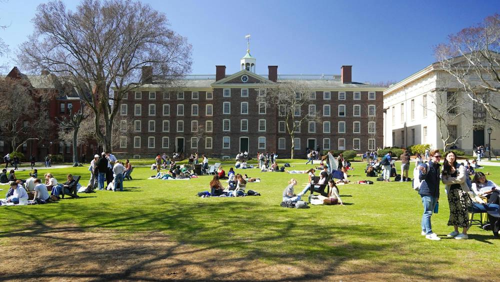 Photo of the Main Green featuring University Hall in the background and students spread out across the lawn walking and sitting.