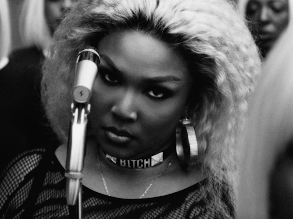 Photo of Lizzo staring at the camera with a microphone next to her face