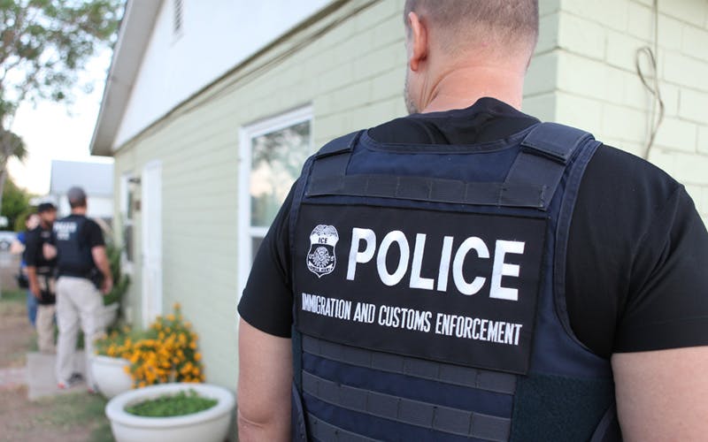 A dark blue jacket has white text that reads "Police" with "Immigration and Customs Enforcement" under it. 