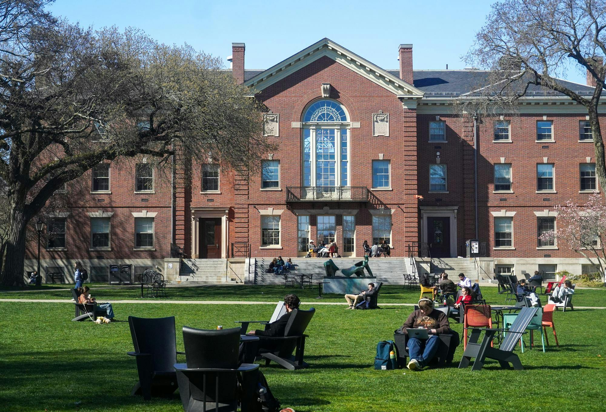 A photo of Brown University’s Main Green facing towards Campus Center with several students sitting on various chairs on a large lawn.