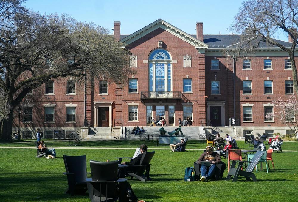 A photo of Brown University’s Main Green facing towards Campus Center with several students sitting on various chairs on a large lawn.