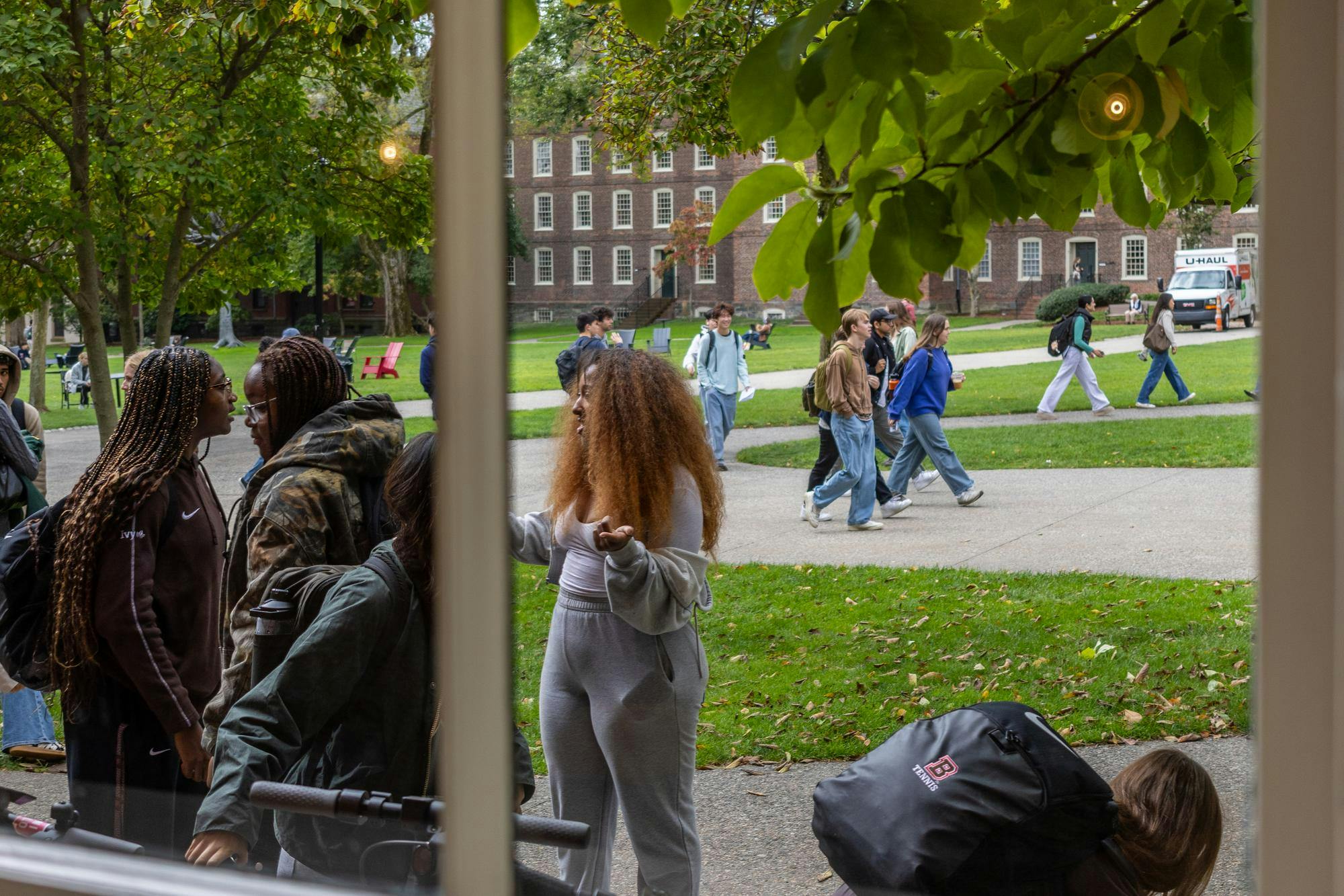 Image looking through a window showing students walking near the Main Green.