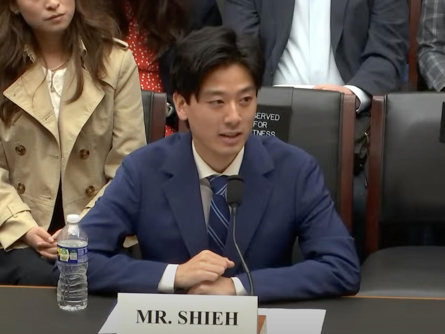 Bloat@Brown creator Alex Shieh ’27 testifying in the congressional hearing Wednesday morning. Shieh is wearing a navy blue suit and sitting in front of a placard labeled "Mr. Shieh."