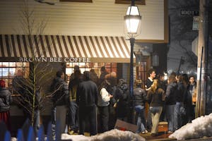 A photo of a long line waiting outside Brown Bee Coffee at night.