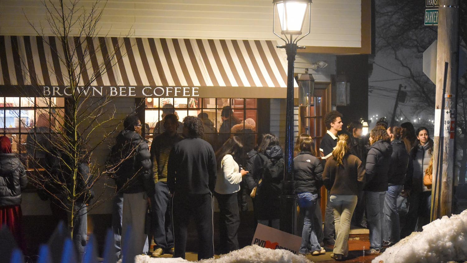 A photo of a long line waiting outside Brown Bee Coffee at night.