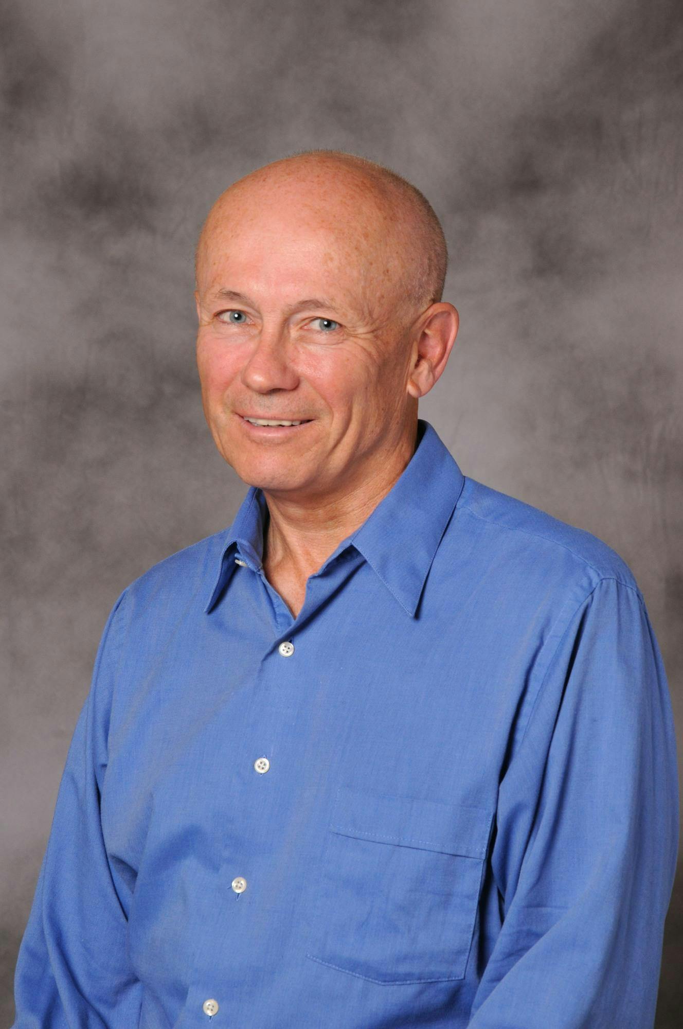 A headshot of Peter Howitt in a blue button-down shirt.