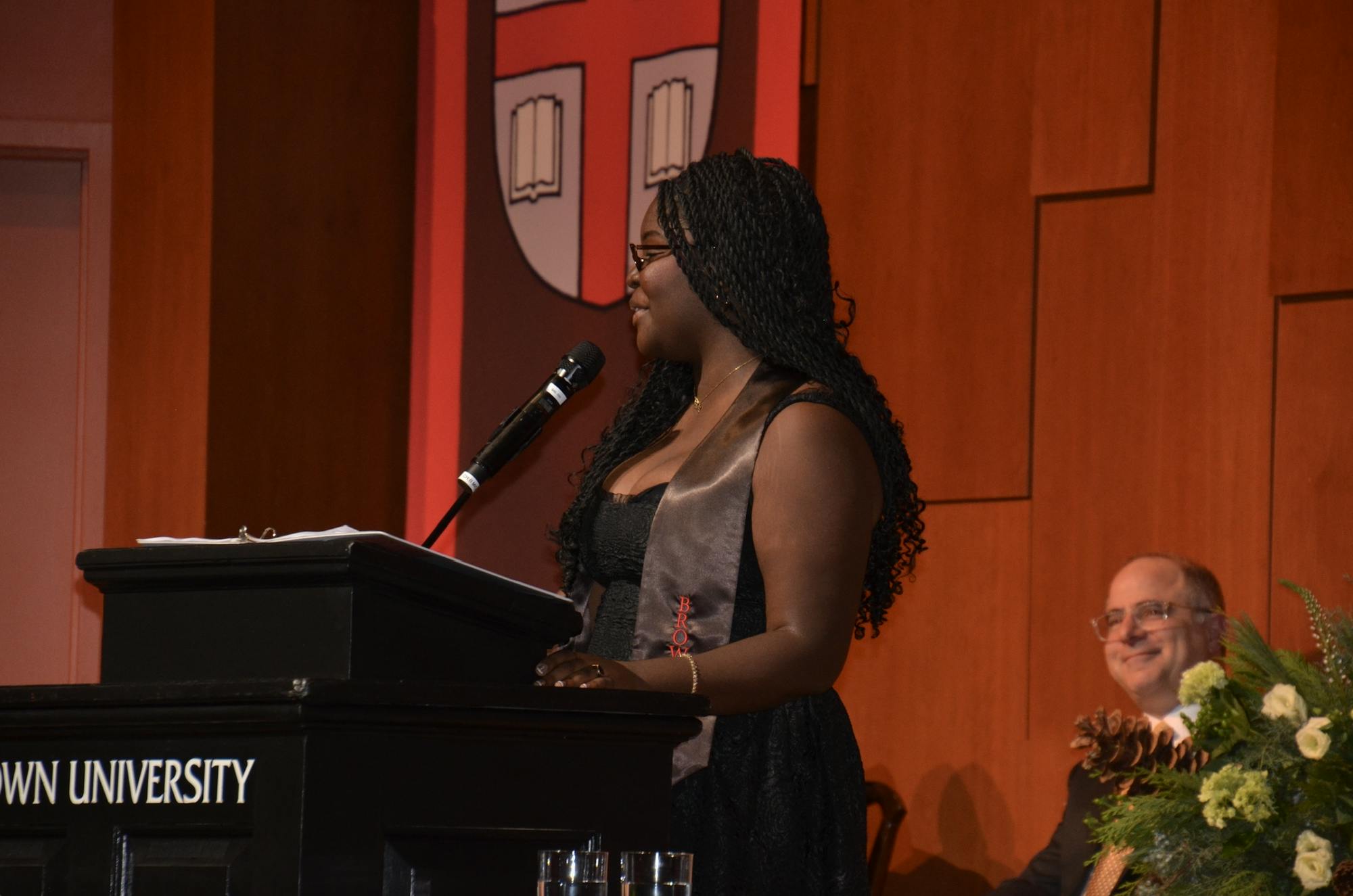 A photo of Vanya Noel giving a speech behind a lectern.