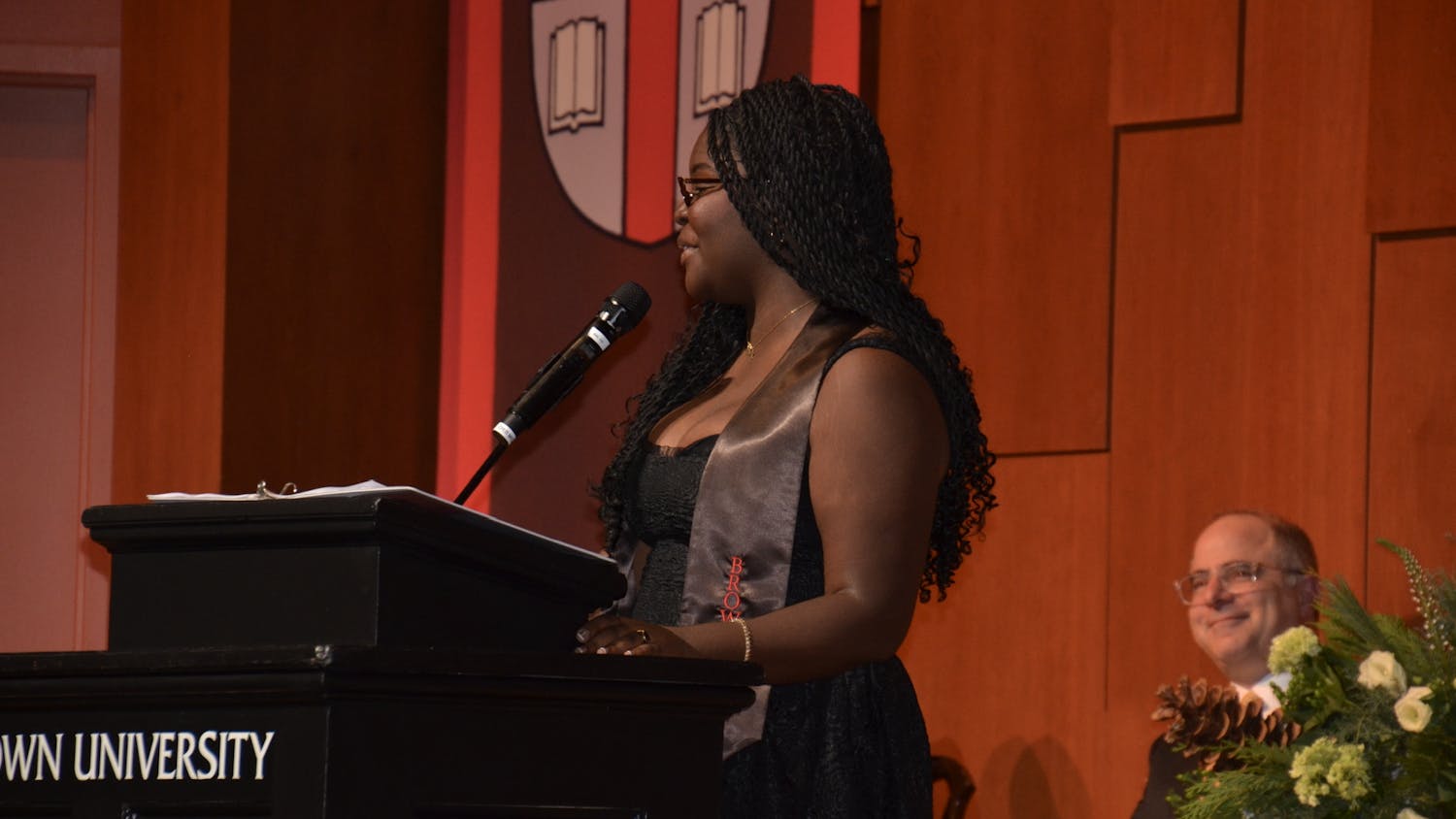 A photo of Vanya Noel giving a speech behind a lectern.